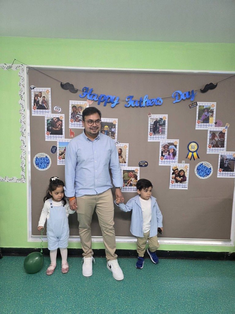 Dad with two children in front of the Happy Father's Day photo wall at Treasure Cove